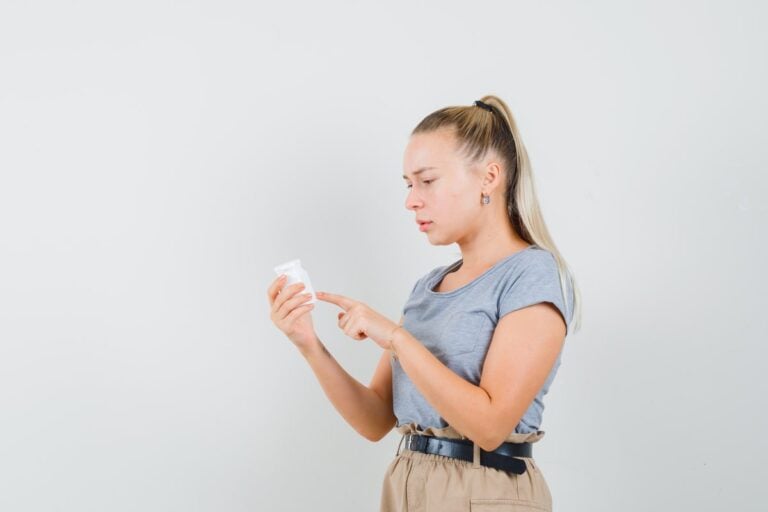 Femme lisant l’étiquette sur l’emballage d’un complément alimentaire